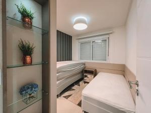 ein kleines Zimmer mit einem Bett und einem Fenster in der Unterkunft 2 Dorm a 100 metros do mar in Capão da Canoa