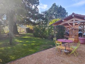 una mesa y sillas en un patio con un árbol en Gîte entre Beaujolais & Mâconnais, en La Chapelle-de-Guinchay