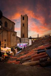 a building with a clock tower in front of a sunset at Duomo Room Comacchio in Comacchio