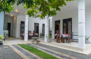 una casa bianca con tavoli, sedie e alberi di Blue Heaven Villa ad Ahangama