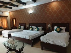 a hotel room with two beds and a table at Royal Ilva Hotel in Lahore