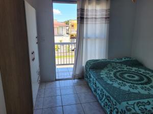 une chambre avec un lit et une porte coulissante en verre dans l'établissement Kit net familia, à São Francisco do Sul