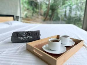 two cups of coffee on a wooden tray on a bed at The Portal Manigala in Matale