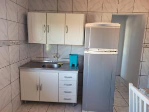 une petite cuisine avec un évier et un réfrigérateur dans l'établissement Kit net familia, à São Francisco do Sul 30 autres photos