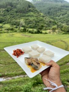 a person holding a white plate with food on it at The Portal Manigala in Matale