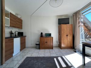 a kitchen with wooden cabinets and a tv on the wall at Appartement pour 4 personnes - Piau Engaly in Aragnouet