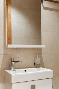 Un baño con un lavabo blanco y un espejo. en Apartmani Zlatni Javor 504 & 514, en Jahorina