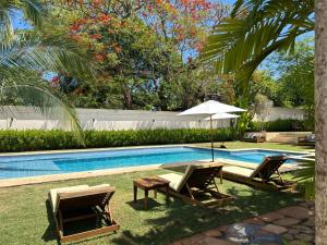 ein Pool mit zwei Stühlen und einem Tisch und einem Sonnenschirm in der Unterkunft Pousada Manacá Exclusive Suítes in Rifaina