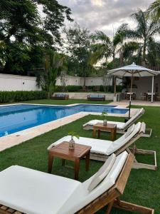 ein Pool mit Liegestühlen und einem Tisch daneben in der Unterkunft Pousada Manacá Exclusive Suítes in Rifaina