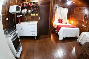 a small room with a bed and a kitchen at Chalé Ipê Amarelo in Juquitiba +42 photos