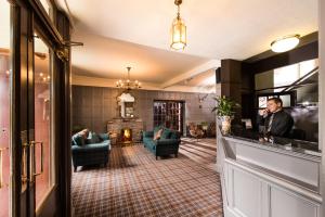 a man standing at a bar in a hotel lobby at Balmoral Arms in Ballater