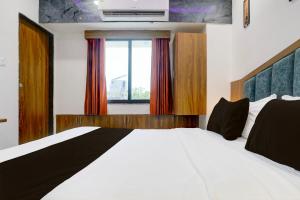 una camera da letto con un letto bianco e una finestra di Hotel O Rion Inn a Ahmedabad Altre 21 foto