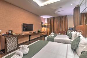 Una habitación de hotel con dos camas y un televisor de pantalla plana. en Hotel COSTAA LA CAGE Near Delhi Airport BY GROSS GROUP, en Nueva Delhi