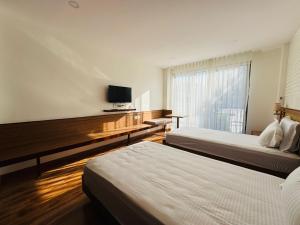 パタンにあるNavaya Residenceのベッド2台と薄型テレビ付きのホテルの部屋