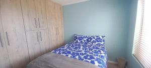 a small bedroom with a bed with a blue wall at Unit 8 Hermanus Beach Club in Hermanus