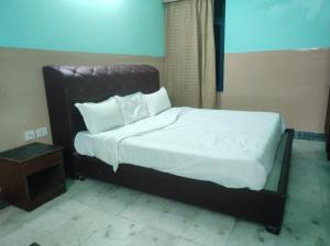 a bed with a black frame and white sheets and pillows at Hotel Blue Bird in Jaipur