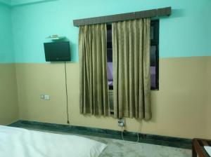a bedroom with a bed and a window with a television at Hotel Blue Bird in Jaipur
