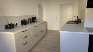 une cuisine avec des armoires blanches et un comptoir dans l'établissement Moderne 3-Zimmer-Ferienwohnung direkt am Saaleradwanderweg, à Halle-sur-Saale 23 autres photos