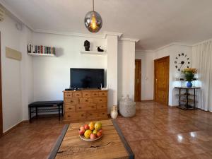 オリウエラにあるFamilienhaus in Cabo Roigのリビングルーム(テレビ付)、フルーツボウル(テーブル上)