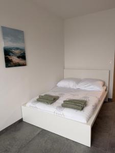 a white bed with two green pillows on it at Królewska 51 in Tuszyn