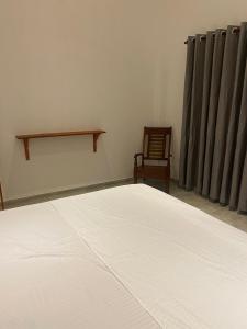 une chambre avec un lit blanc et une chaise dans l'établissement Costal View, à Ahangama