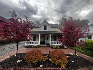 une maison blanche avec des arbres fleuris devant elle dans l'établissement Driftwood on 6th Heritage Downtown Collingwood, à Collingwood