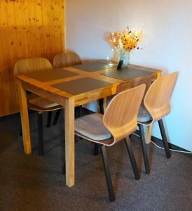 een houten tafel met stoelen en een vaas met bloemen bij Frühstückspension Malu in Todenbüttel