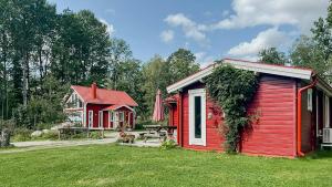 a red cabin with a picnic table next to a house at Modern Loft House In The Woods Near Gullabo in Gullabo