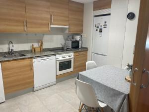 a kitchen with white appliances and a table with chairs at El Rincón del Ángel in Jaca
