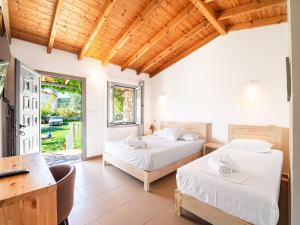 two beds in a room with a kitchen and a desk at Janakis Garden Livadi Beach in Spile