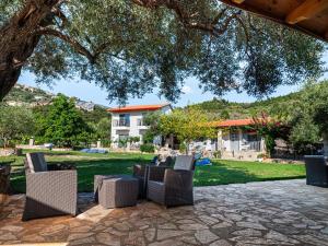 a group of chairs sitting on a patio under a tree at Janakis Garden Livadi Beach in Spile