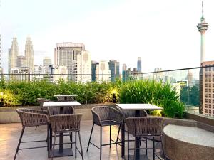 Un patio con mesas y sillas y vista a la ciudad. en Kuala Lumpur Luxury Suites By Majestic Residence, en Kuala Lumpur