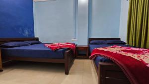 two beds in a room with blue walls at Mountain Rooms And Homestay in Vagamon