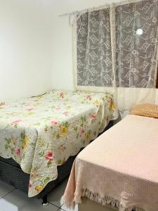 una camera con 2 letti e una coperta floreale di Apartamento mobiliado em Florianópolis a Florianópolis