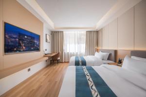 een hotelkamer met twee bedden en een tv bij Wanxin Zhige Hotel in Zhangla