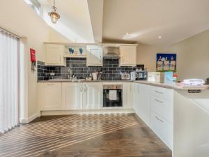 a kitchen with white cabinets and black tiles at The Parlour in Ferndown +6 photos