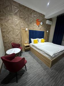 een hotelkamer met een bed en twee stoelen bij Tahtapul Expo Hotel in Tasjkent