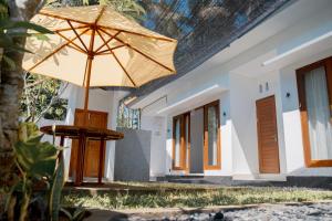 a table with an umbrella in front of a house at Padma Graha Villa in Candidasa