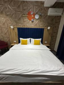 een bed met twee gele kussens en een klok aan de muur bij Tahtapul Expo Hotel in Tasjkent +7 foto's