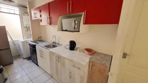 a small kitchen with red cabinets and a sink at D14-9 Arriendo diario a pasos de la playa Arica in Arica