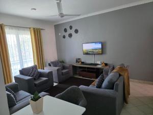 a living room with couches and a flat screen tv at SaltyNest in Gatunga