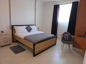 a bedroom with a bed and a chair and a window at SaltyNest in Gatunga