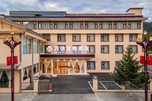 een groot roze gebouw met een bord erop bij Wanxin Zhige Hotel in Zhangla