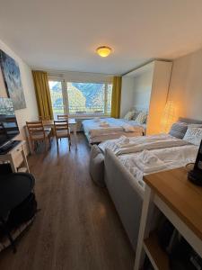 アローザにあるFortuna 8 by Arosa Holidayのベッド3台とテーブルと椅子があるホテルの部屋