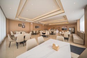 een eetkamer met witte tafels en stoelen bij Wanxin Zhige Hotel in Zhangla +15 foto's