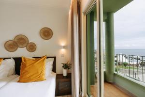 a bedroom with a bed and a balcony with the ocean at Hotel Euro Moniz in Porto Moniz