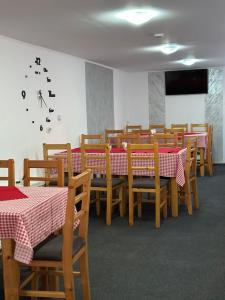 a dining room with tables and chairs and a clock on the wall at Pensiunea Maria in Lacu Rosu