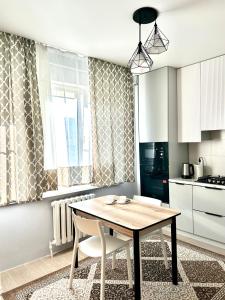 a kitchen with a wooden table and chairs in a room at 1 комнатные апартаменты in Atyraū