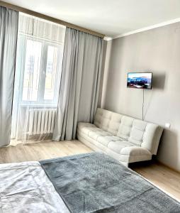 a living room with a white couch and a window at 1 комнатные апартаменты in Atyraū