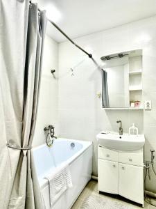 a white bathroom with a tub and a sink at 1 комнатные апартаменты in Atyraū